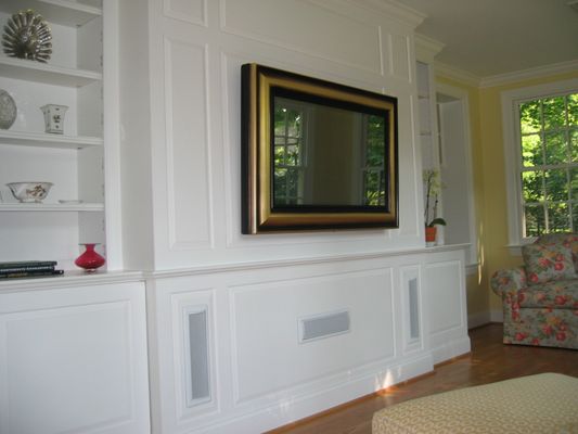 Television behind mirror. Surround sound system integrated into wood work.