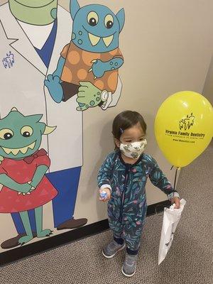 2 year old daughter in mask with balloon and bouncy ball after appointment