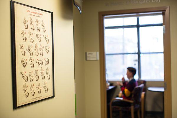 The Deaf & Hard of Hearing Services hallway at HSDC. A Deaf person is signing inside an office.