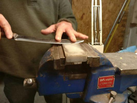 A knife being honed on an oil stone.