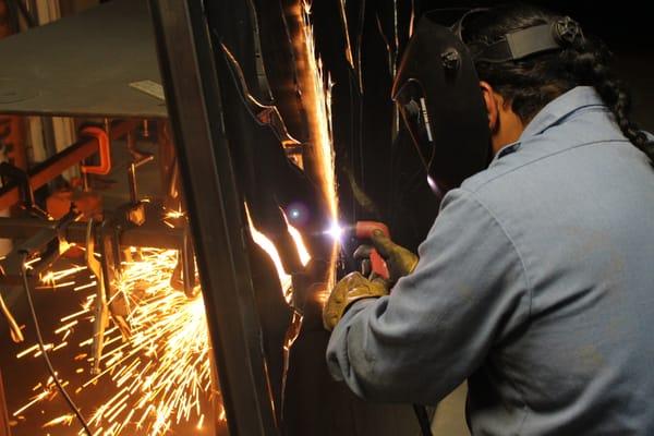 Using the plasma cutter to cut out the tree designs in steel panels.