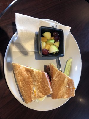 Italian sandwich  with a side of fruit salad.