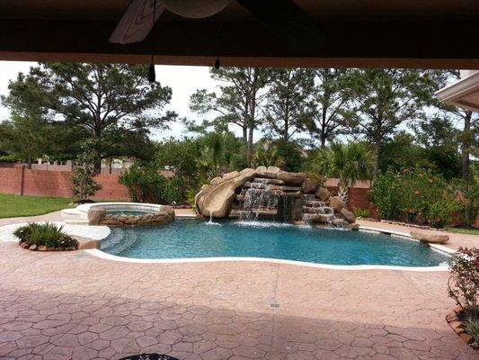 Pool, spa, waterslide, cave, and waterfall. Stamped concrete.