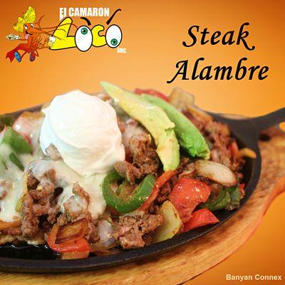 Our Steak Alambre is a skillet with sliced green and red bell peppers, jalapenos, onions, bacon and ham; topped with melted cheese & more.