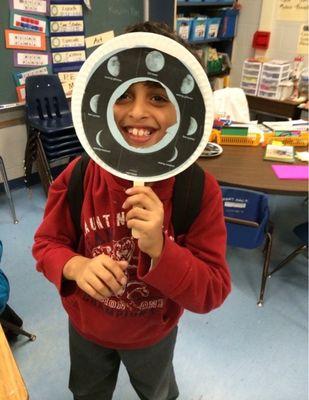 A kid showing the moon phases in class