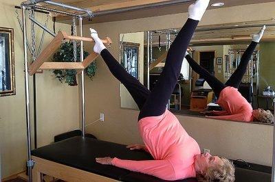 80 year-old client performing a shoulder bridge movement on the Pilates Cadillac.