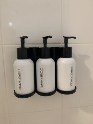 Large shampoo and conditioner bottles in the shower.