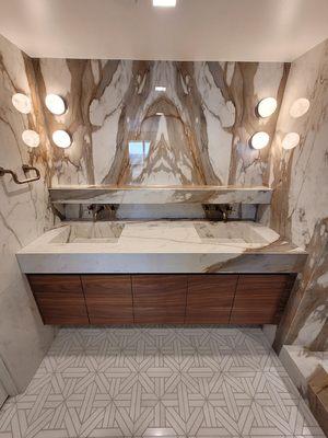 Italian porcelain book-matched wall panels and two custom integrated sinks.