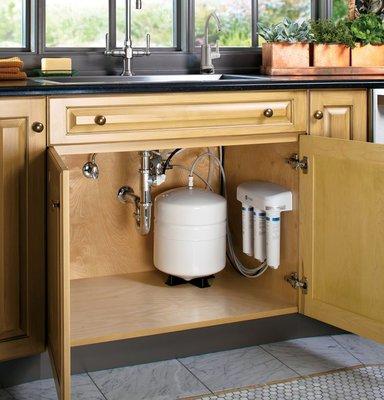 A reverse osmosis system installed under the kitchen sink feeding a separate faucet and a refrigerator dispenser.