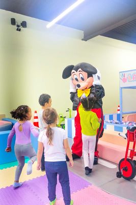 Mickey character plays with children