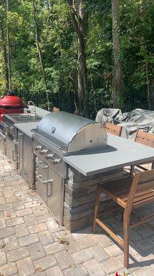 Outdoor straight kitchen with extra countertop overhang for additional seating.  Ledge stone patterned panel.