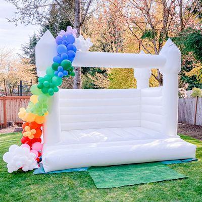 White bounce house with balloon garland