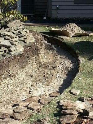 Laying the foundation of a new dry stack river stone retaining wall.