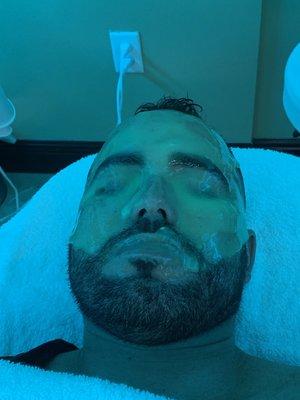 Completing his facial with a individualized mask