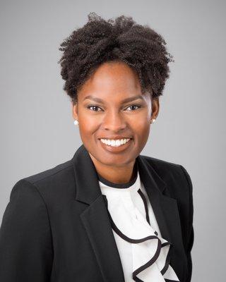 A modern business headshot on a gray background.