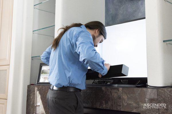 Audio video technician installing and mounting a sound bar