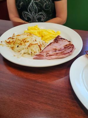 Scrambled eggs, hashbrowns,ham and a side of bacon.