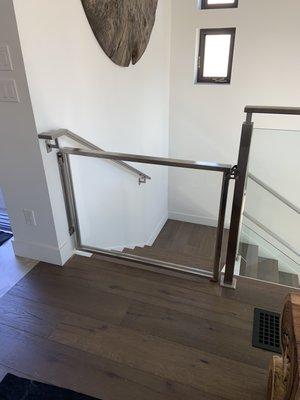 Stainless baby gate with inset glass made to match existing stair rail.