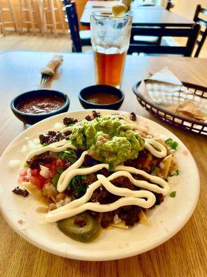 Carne Asada nachos with guacamole, chips and red and green salsa with iced tea.