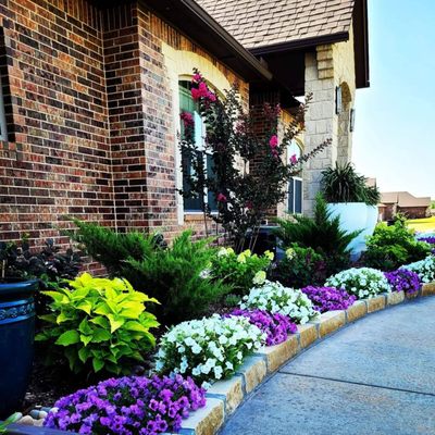 Check out this beautiful chopped stone flower bed, enhanced with a vibrant array of colorful flowers.