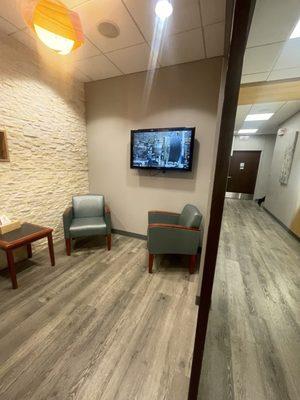 The hallway with the small area wait room with a tv