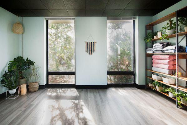 Blueberry Sage's intimate yoga studio has floor-to-ceiling windows framing nature's beauty, creating a serene space for practice.