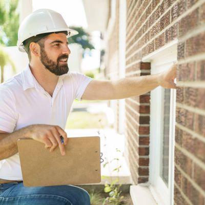 Secured Inspector with a white hard hat holding a clipboard, inspect house