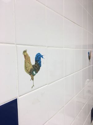 A chicken pooping is the decor in the men's loo?