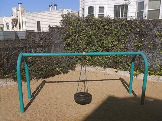 Tire swing in the back corner of the park