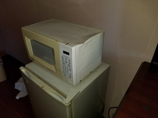 Old, dented, and cigarette burned microwave.