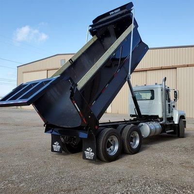 A dump bed being raised by a hydraulic telescopic arm.