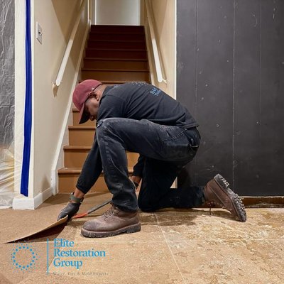 photo of one of the team removing tiles from the ground that being damage with water cause by flood