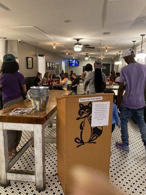 Crowded waiting area, people sitting and ordering yummy Fox Ridge delicious pizza