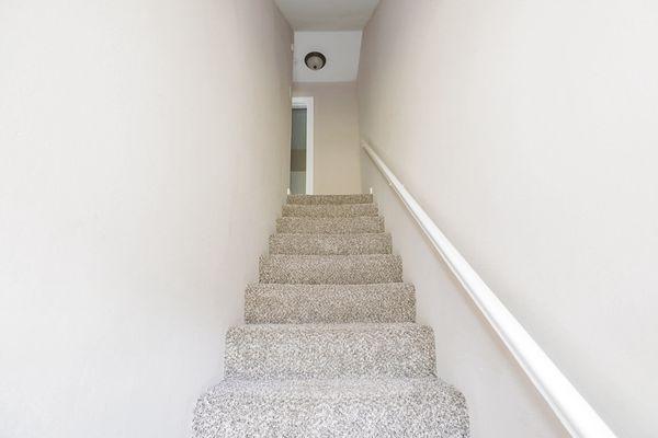 CARPETED STAIRWAY WITH WALL TO WALL CARPET UPSTAIRS.