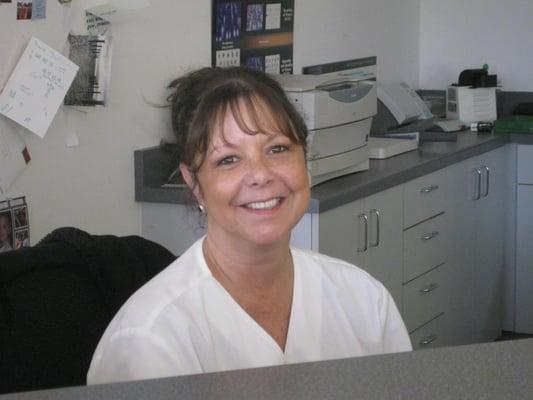 A smiling Lisa, assisting the front desk.