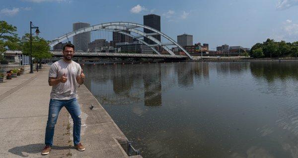 Owner, Brett Iwanowicz in Corn Hill with the Rochester Skyline in the background