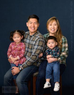 Family of 4  photo session in studio on blue backdrop.