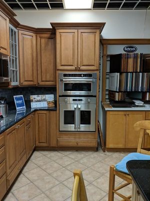 kitchen showroom with wooden cabinetry, tile flooring,  and two built in stainless steel wall ovens