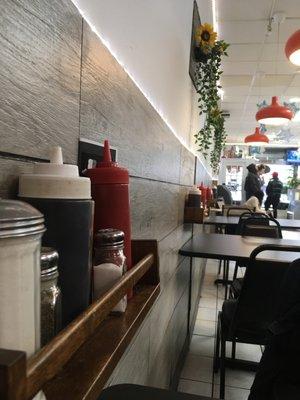 Smart use of shelving at each table to keep condiments up off the table top clean and available