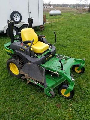 Danny and Neal stand behind their used mowers, like this 2006 John Deere.