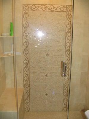 New bathroom remodel with custom tile design, bench seat, shelves and glass shower door.