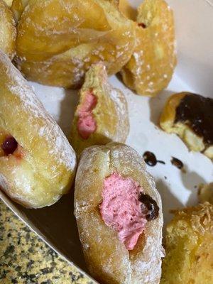 Some filled donut varieties. The chocolate dripped on the raspberry cream accidentally