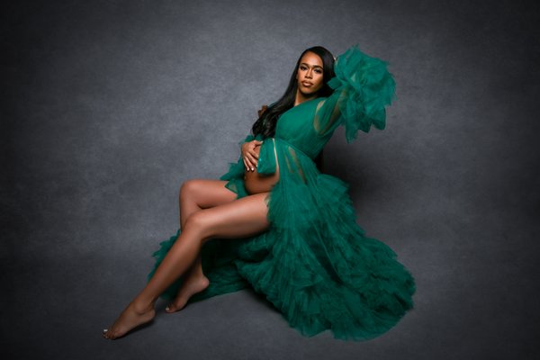 Maternity Elegant Woman with a Big Ruffled Green Dress on a Canvas Background