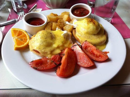 Eggs Benedict with side of country potatoes and roasted tomatoes.