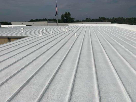 Finishing spray foam on standing seam metal roof.