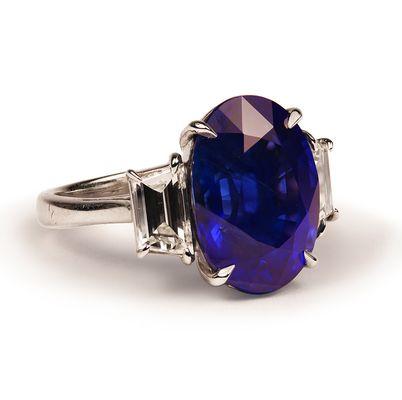 Oval Blue Sapphire & Diamond Ring, accompanied by 10.70 carats of a large center Blue Sapphire and (2) Trapeze Diamonds.