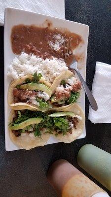 Beef tacos with avocado, cilantro, onion and spicy red and green sauces