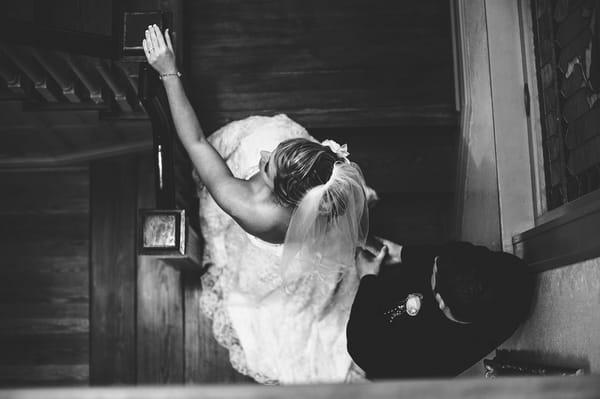 An elegant bride and groom walking up the stairs in an old Victorian home.