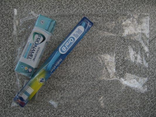 Goody bag with a new tooth brush, tooth paste & floss.