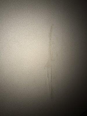 Some sort of splatter on the wall next to the bed